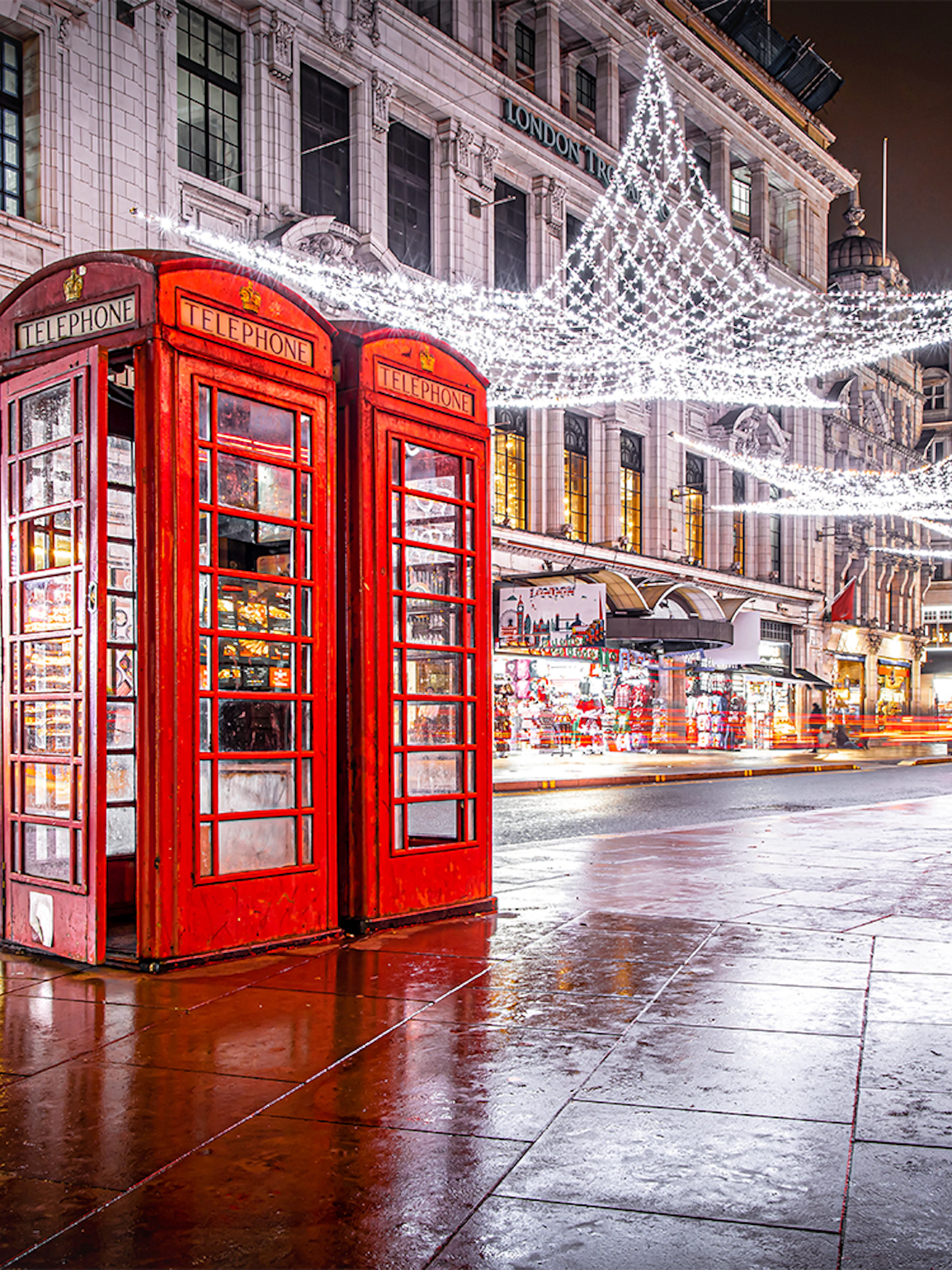 Red phone booth near Leicester Square with Christmas lights and decorations.