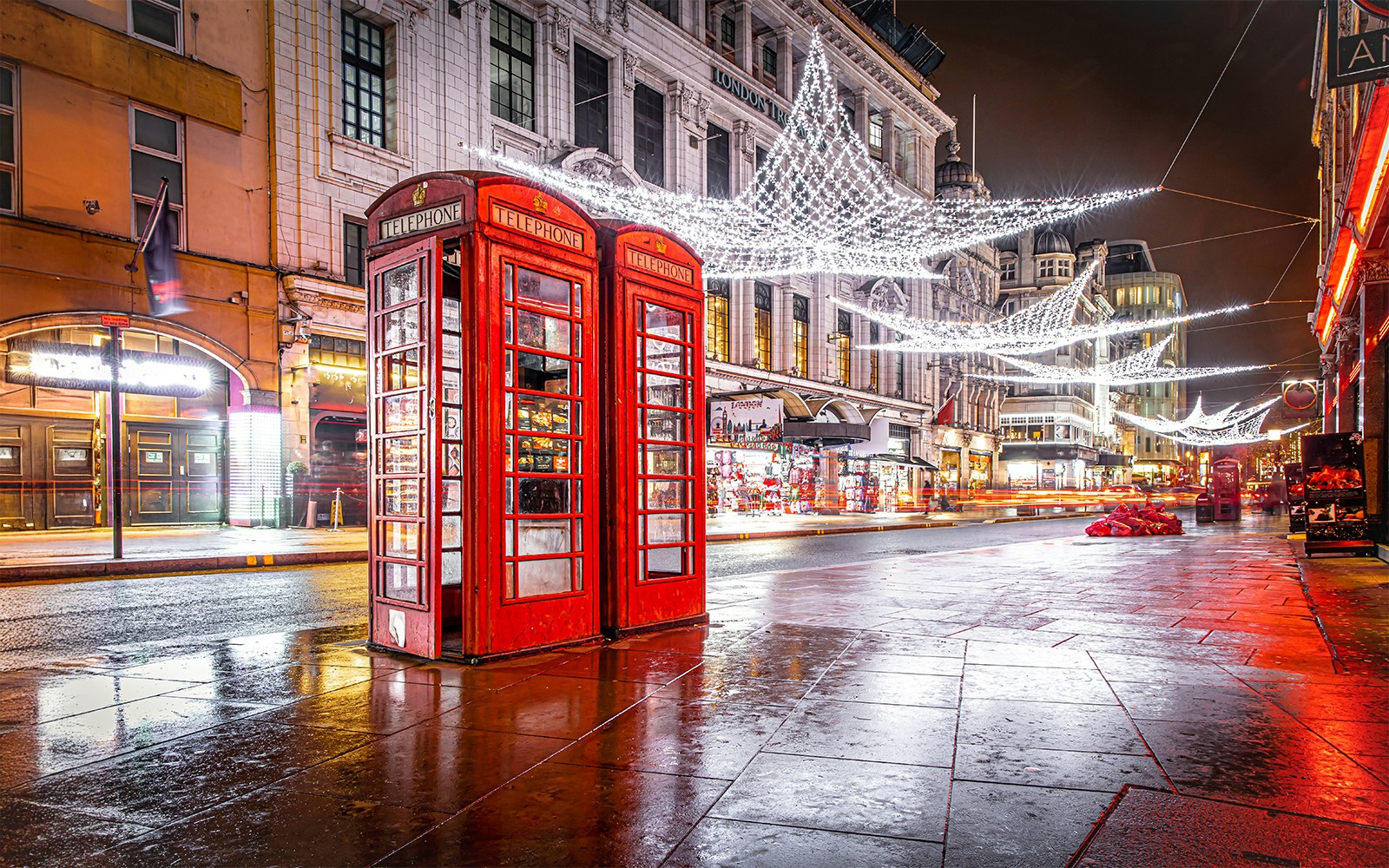 Red phone booth near Leicester Square with Christmas lights and decorations.