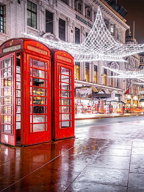 Red phone booth near Leicester Square with Christmas lights and decorations.