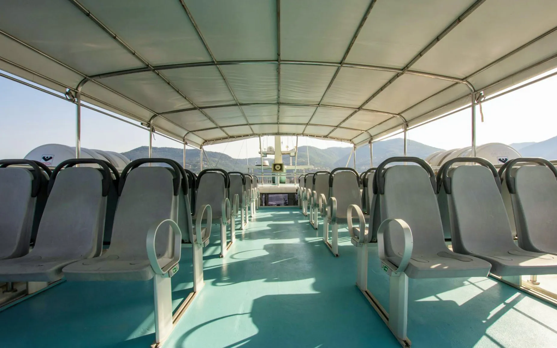 Open-air seating on a cruise boat with mountain views in Cinque Terre.