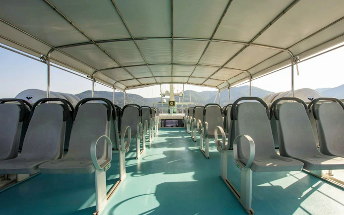 Open-air seating on a cruise boat with mountain views in Cinque Terre.
