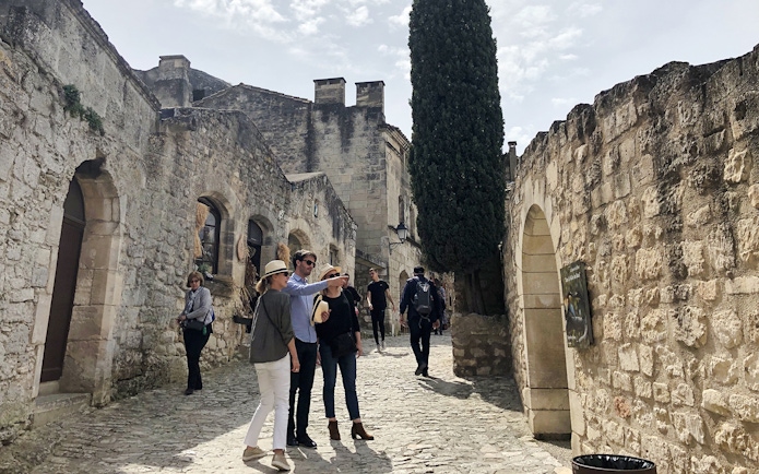 Visitors exploring historic stone streets in Les Baux De Provence, Provence, France.