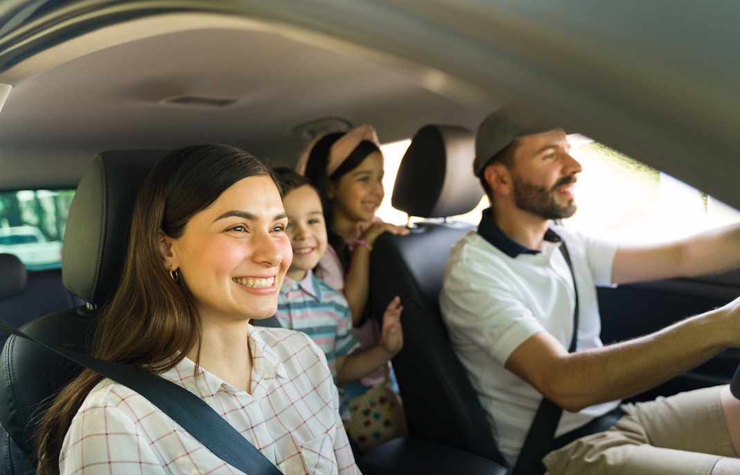 Family enjoying a scenic drive in a car through countryside.