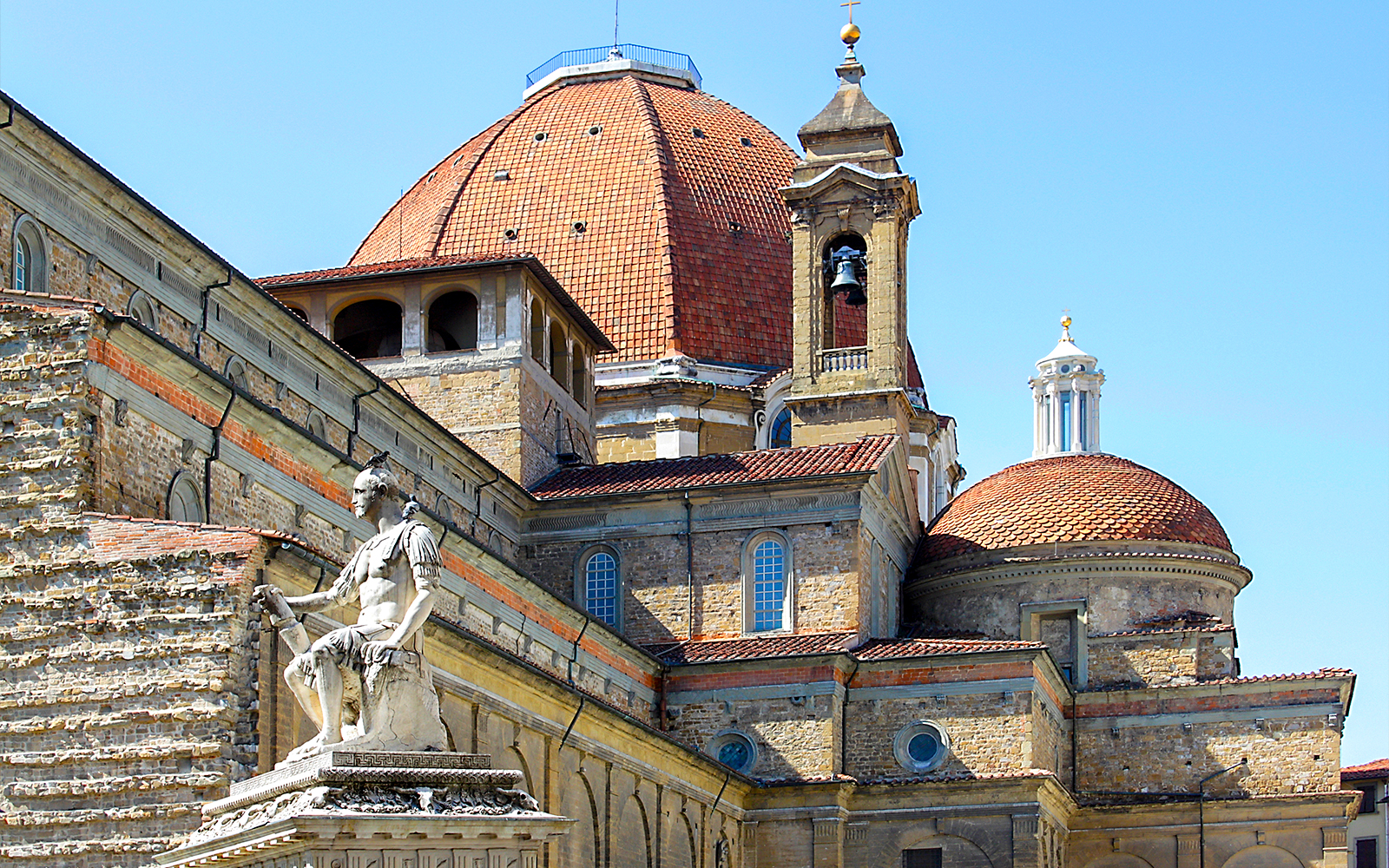 Renaissance architecture of Florence's Basilica di San Lorenzo with statue in foreground.