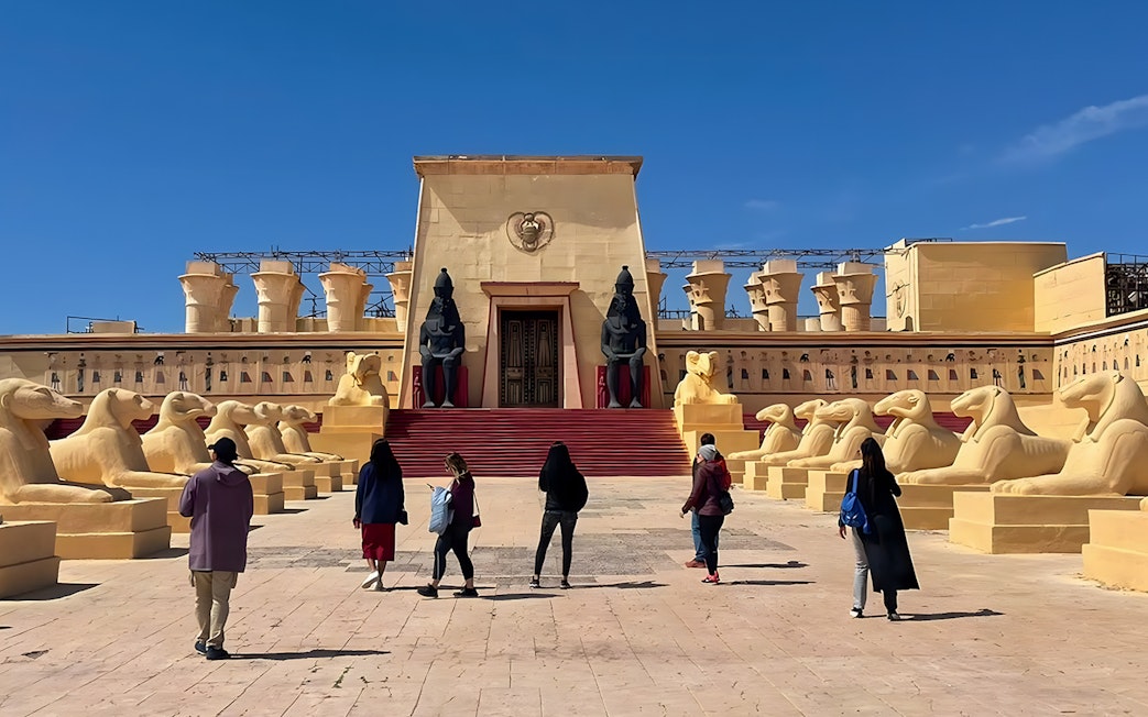 Visitors walking towards ancient Egyptian set at Atlas Studios, Ouarzazate, Morocco.