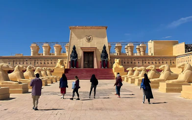 Visitors walking towards ancient Egyptian set at Atlas Studios, Ouarzazate, Morocco.