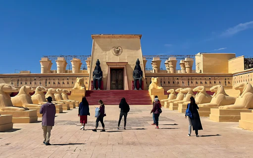 Visitors walking towards ancient Egyptian set at Atlas Studios, Ouarzazate, Morocco.