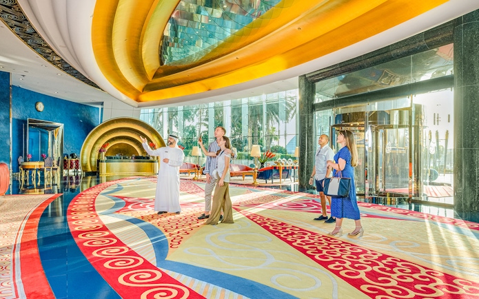Tour group inside Burj Al Arab lobby with guide, vibrant decor, Dubai.