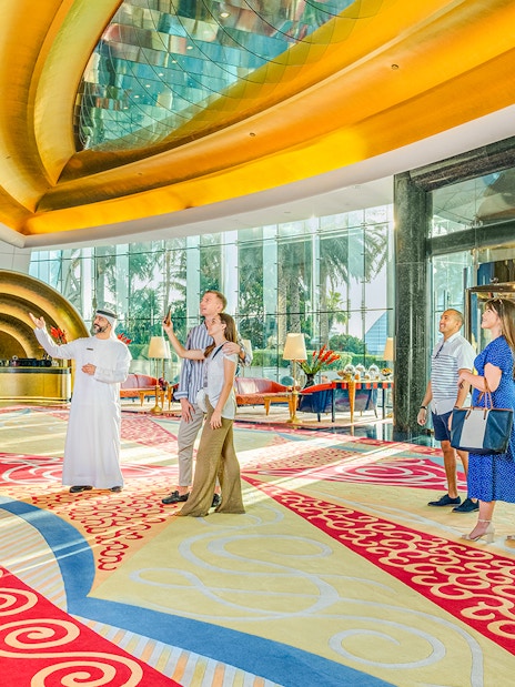 Tour group inside Burj Al Arab lobby with guide, vibrant decor, Dubai.