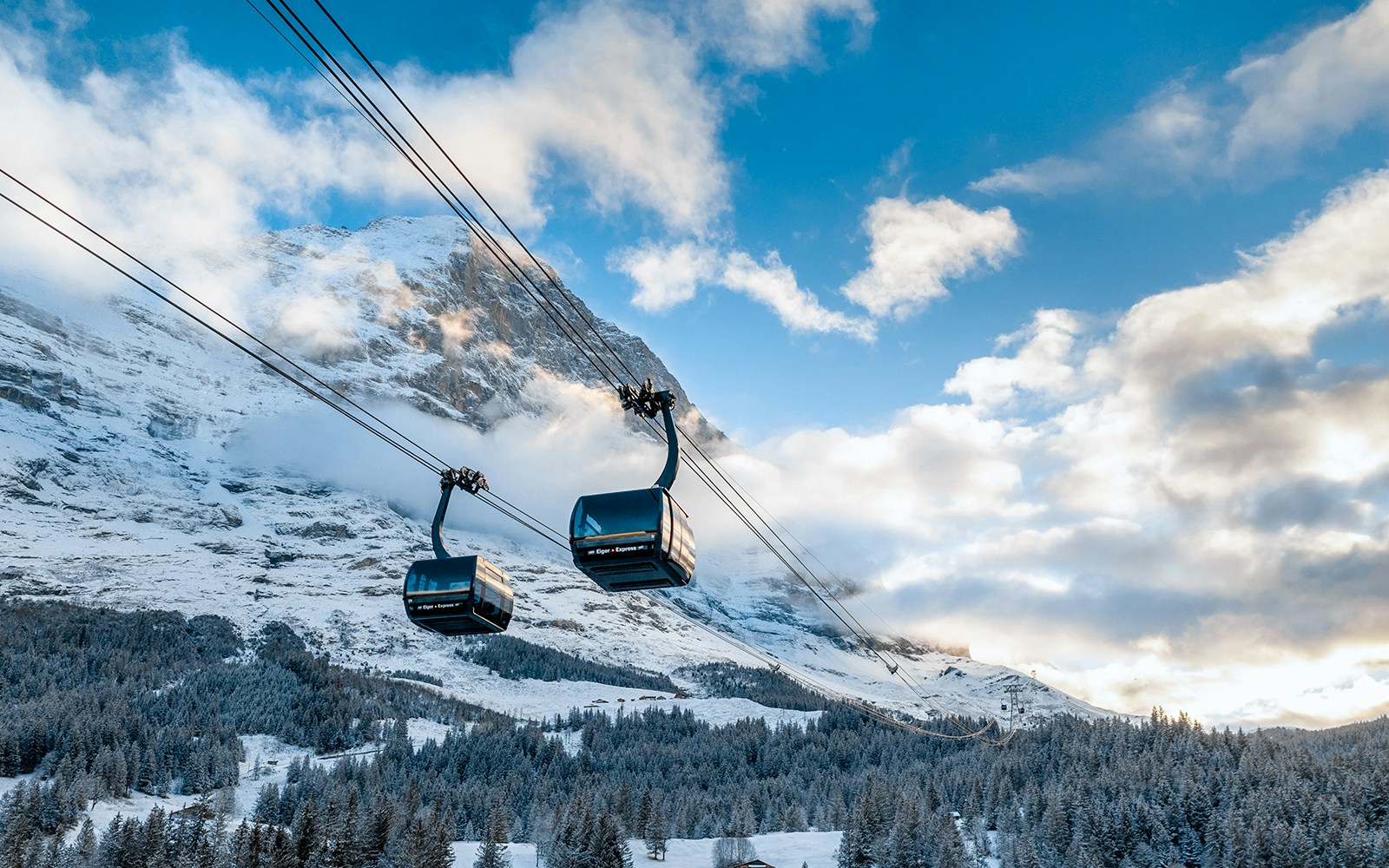 Eiger Express gondola ascending to Jungfraujoch with snowy mountain backdrop.