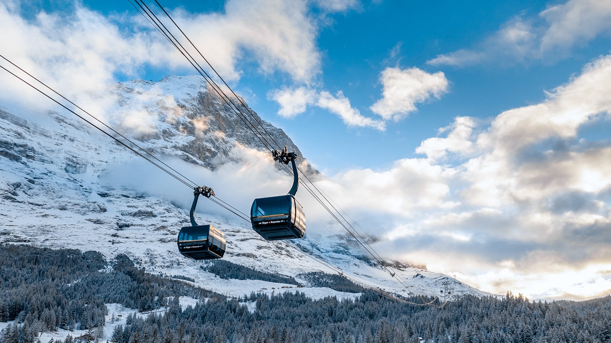 Eiger Express gondola ascending to Jungfraujoch with snowy mountain backdrop.