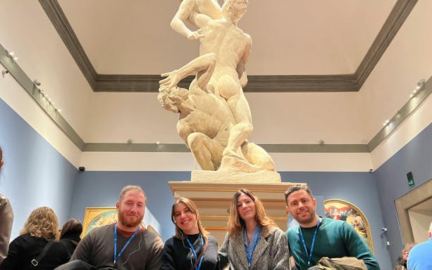 Visitors in front of a classical sculpture at a museum.