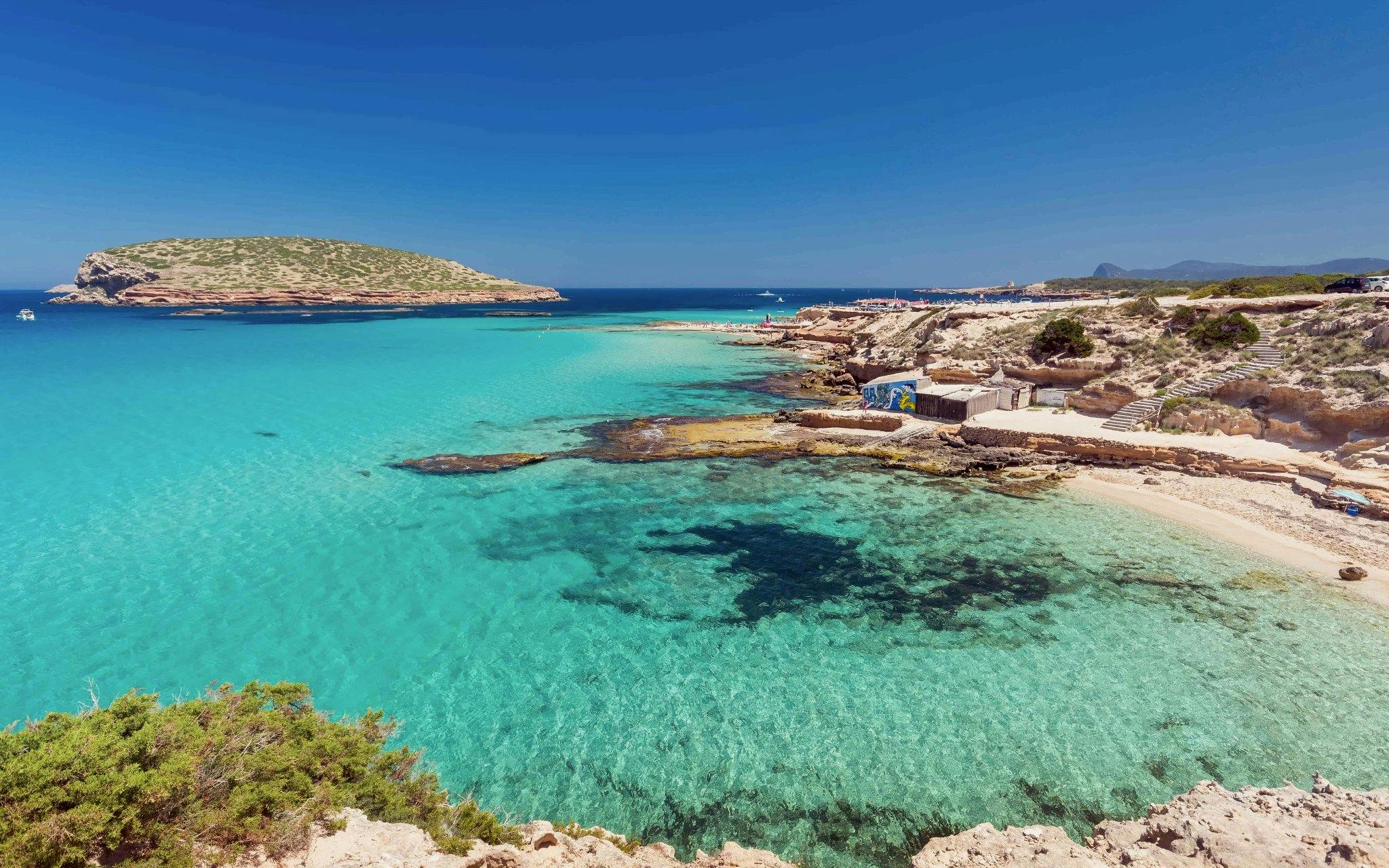 Cala Bassa Beach with clear turquoise water and rocky coastline in Ibiza, Spain.