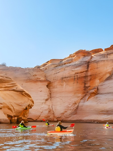 Kayakers paddling on Lake Powell near Antelope Canyon's sandstone cliffs.