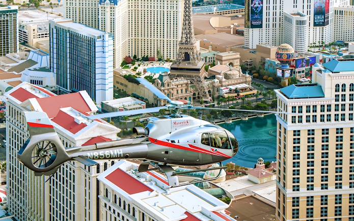 Maverick Helicopter flying over the Las Vegas Strip with city landmarks below.