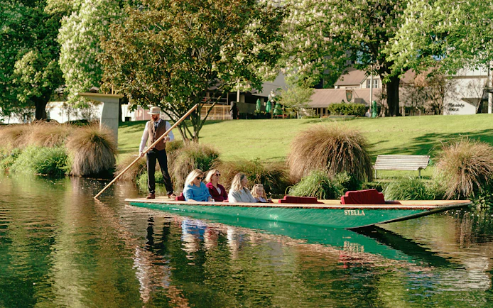 Punting on the Avon River in Christchurch with passengers enjoying the scenic view.