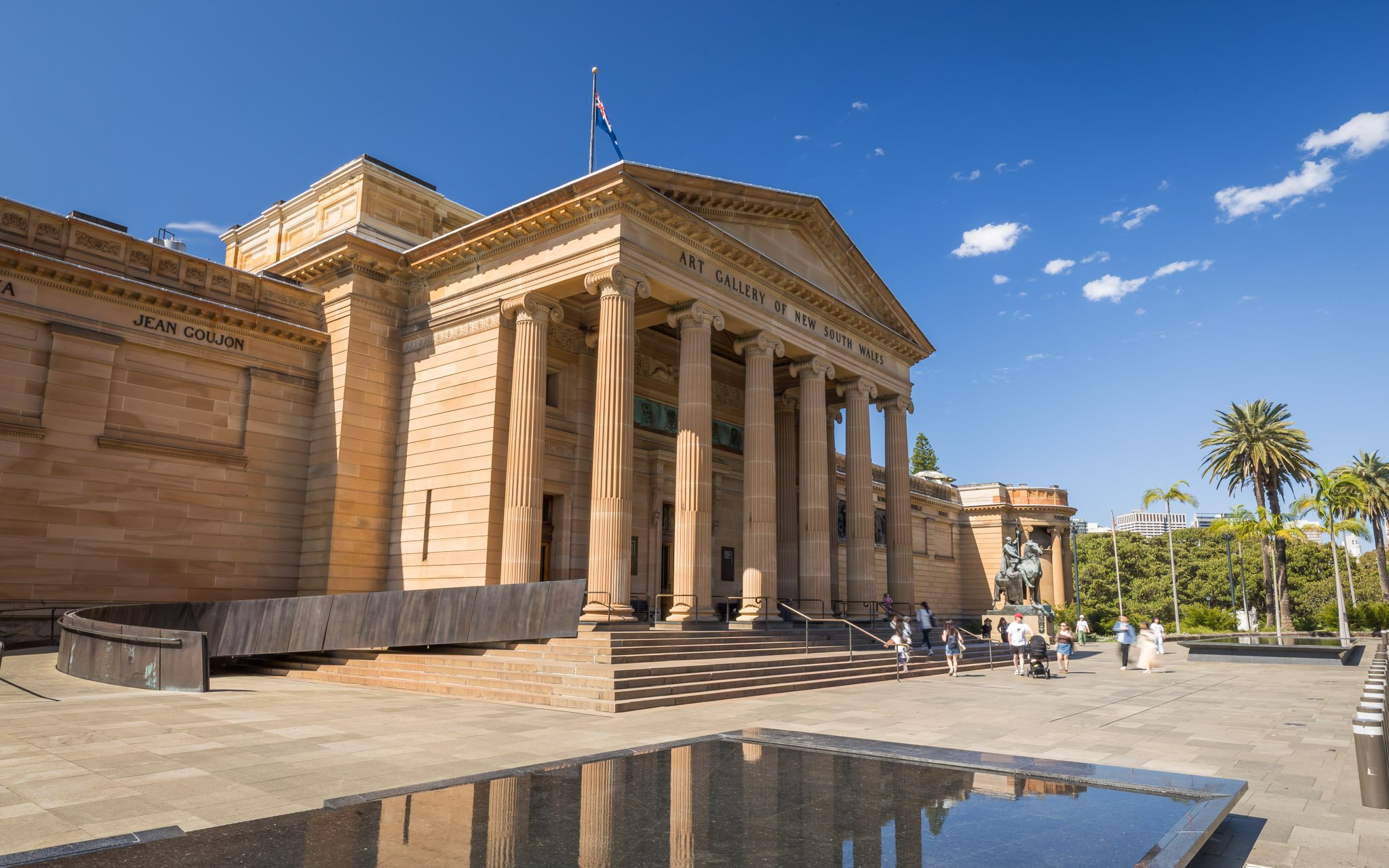 Entrance of Art Gallery of New South Wales, Sydney with visitors and surrounding palm trees.