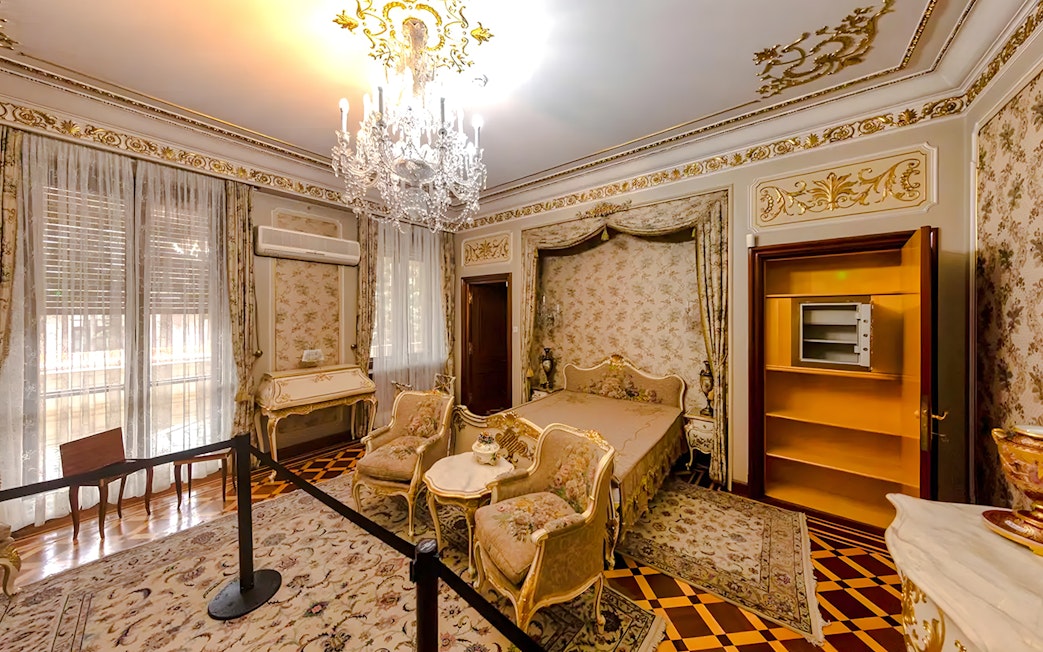 Interior of Ceaușescu Mansion bedroom with ornate decor and chandelier, Bucharest.