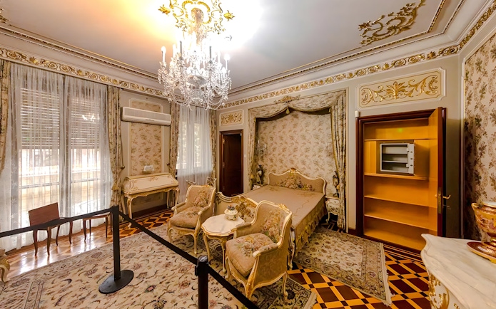 Interior of Ceaușescu Mansion bedroom with ornate decor and chandelier, Bucharest.