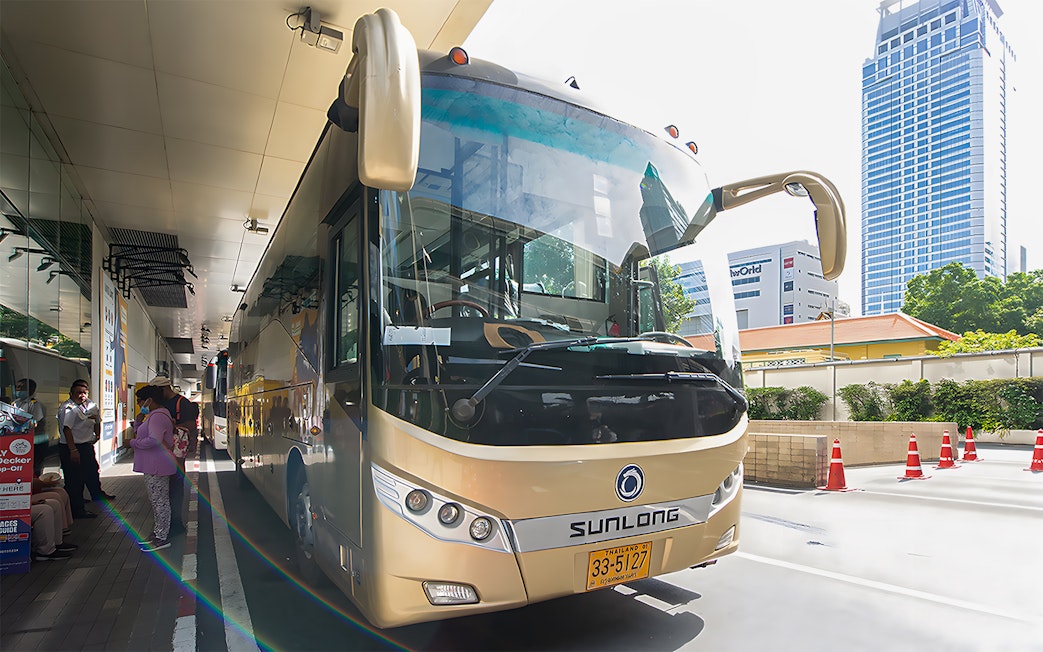 Tour bus parked at a station, ready for the Damnoen Saduak Floating Market & Maeklong Railway Market tour.