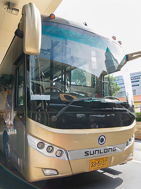 Tour bus parked at a station, ready for the Damnoen Saduak Floating Market & Maeklong Railway Market tour.