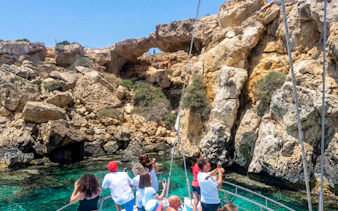 Tourists on a boat photographing sea caves near Protaras during Blue Lagoon cruise.