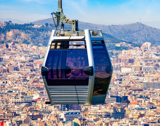 Montjuic Cable Car over Barcelona cityscape with mountains in the background.