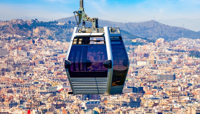 Montjuic Cable Car ascending with panoramic view of Barcelona cityscape.