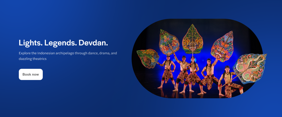 Dancers in traditional costumes holding colorful leaf props at Devdan Show, Bali.