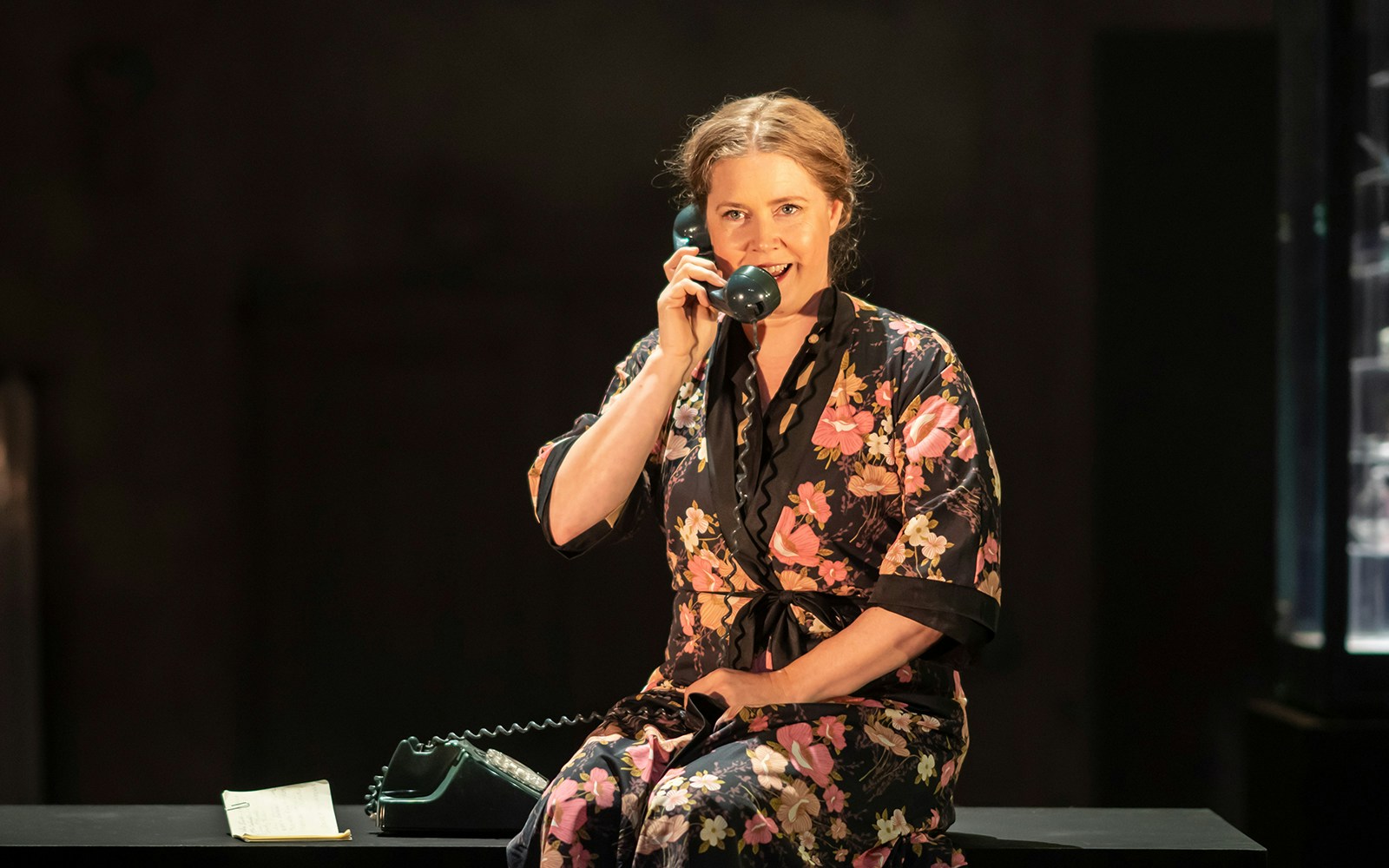 Woman in floral robe speaking on a vintage phone during The Glass Menagerie performance.