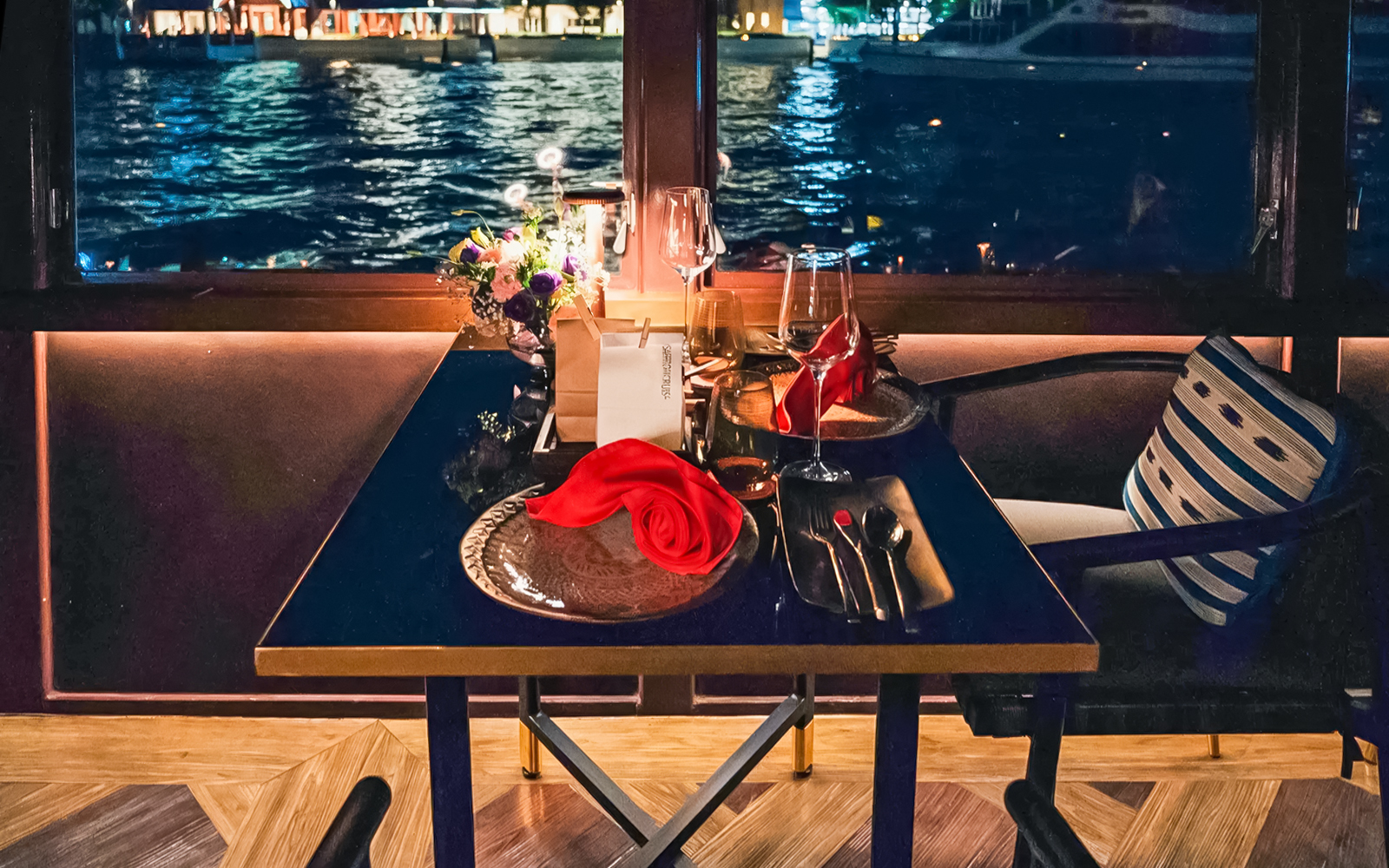 Elegant dining setup on Saffron Luxury Cruise by Banyan Tree with waterfront view.