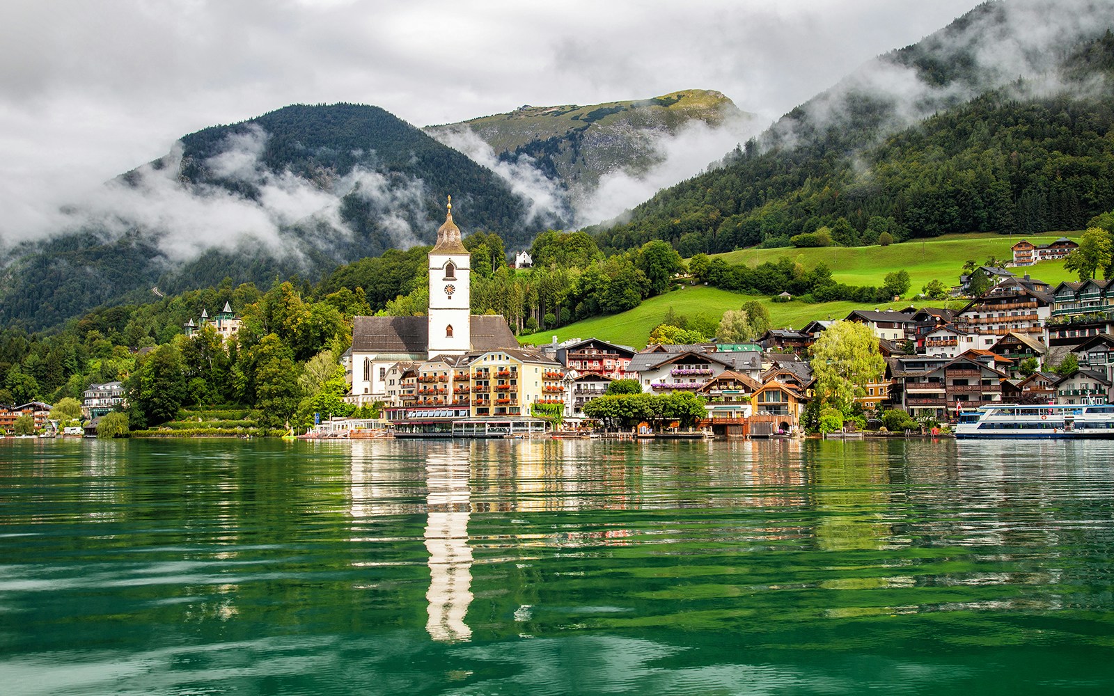 St. Wolfgang town and church by Lake Wolfgang, Salzkammergut, with mountains in the background.