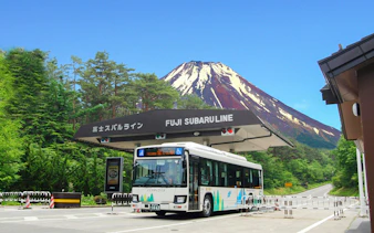 Bus at Fuji Subaru Line gate with Mt. Fuji in the background, Japan.