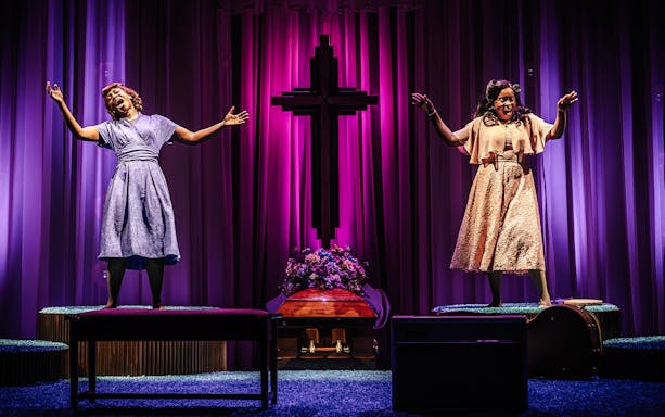 Performers singing on stage in Marie & Rosetta production with purple backdrop and cross.