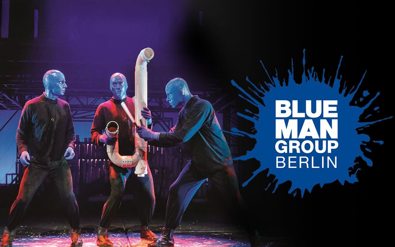 Blue Man Group performers with instruments on stage in Berlin.