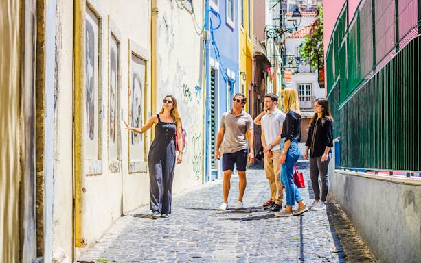 Tour group with guide exploring colorful street in Lisbon.