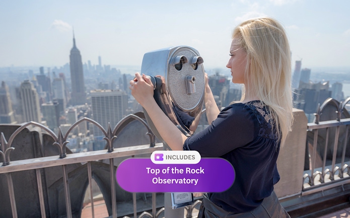 Person using binoculars at Top of the Rock Observatory, New York City skyline in view.