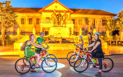 Cyclists in front of the Three Kings Monument during Chiang Mai night bike tour.