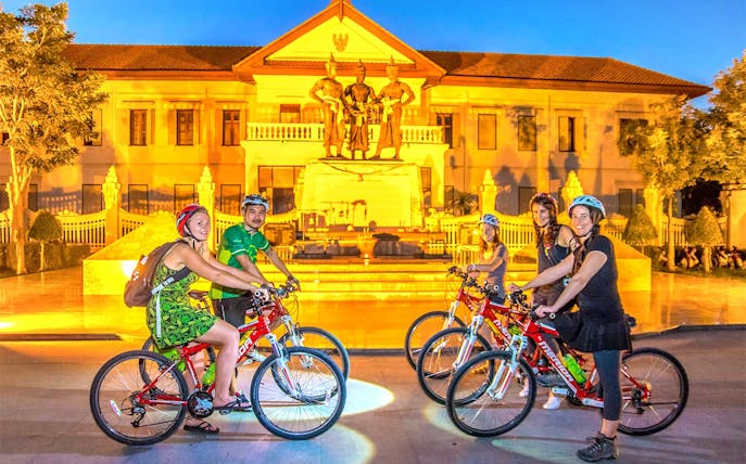 Cyclists in front of the Three Kings Monument during Chiang Mai night bike tour.