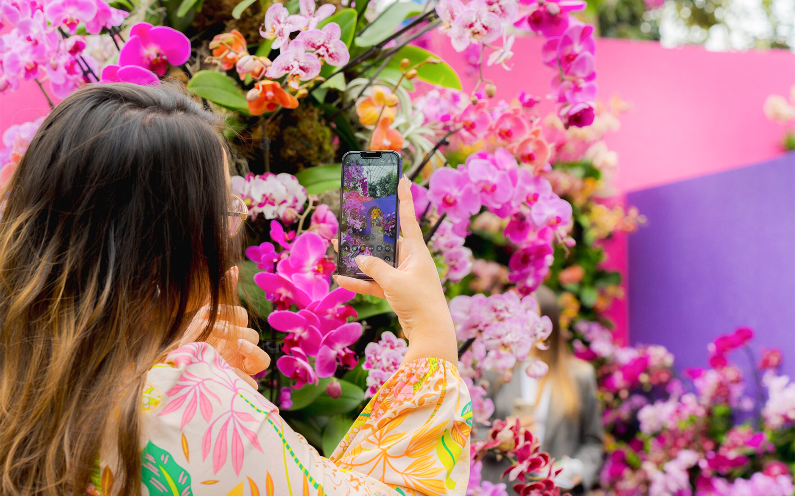 Woman photographing orchids at the Orchid Show, New York Botanical Garden.