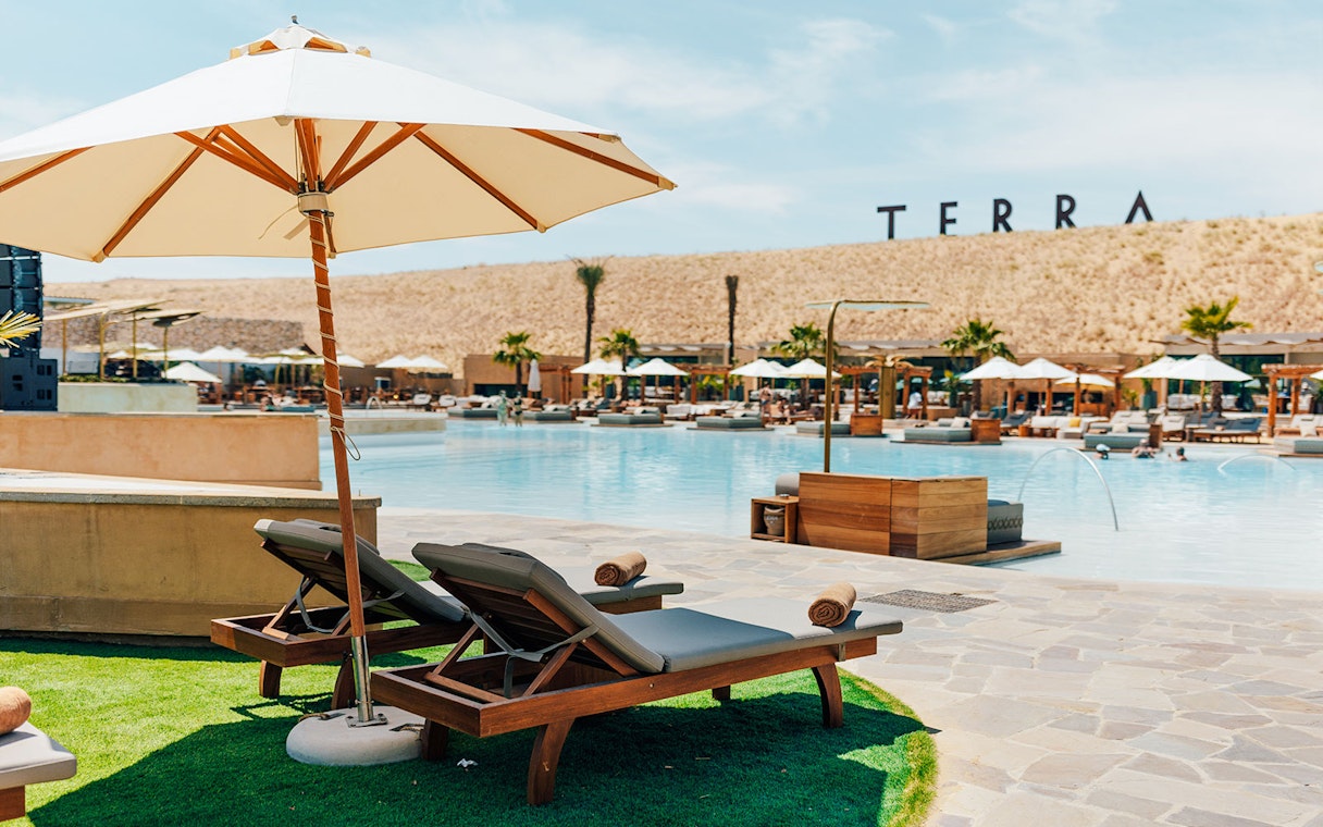 Sun loungers by the pool at Terra Solis with desert backdrop.