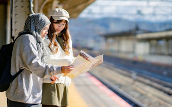 Two tourists reading a map at a train station in Japan.