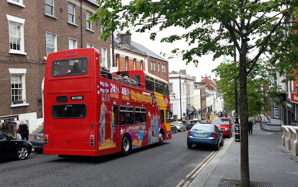 Red double-decker bus on Derry street during Hop-On-Hop-Off tour.