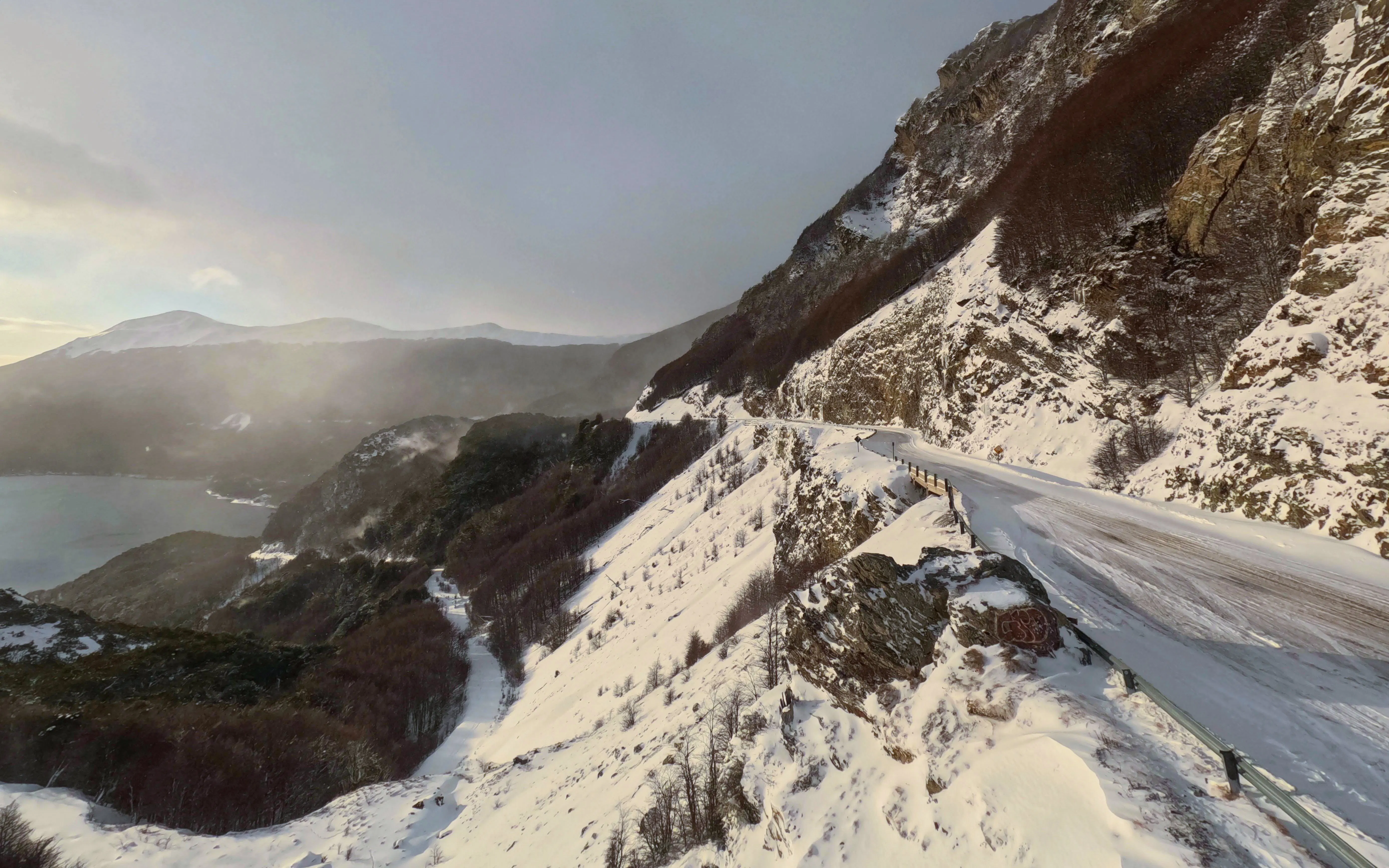 Snow-covered mountain road in Ushuaia, Argentina, with scenic views of distant peaks and valleys.