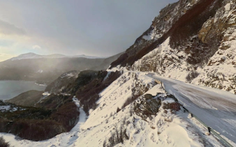 Snow-covered mountain road in Ushuaia, Argentina, with scenic views of distant peaks and valleys.