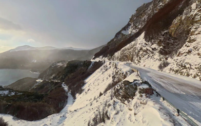 Snow-covered mountain road in Ushuaia, Argentina, with scenic views of distant peaks and valleys.