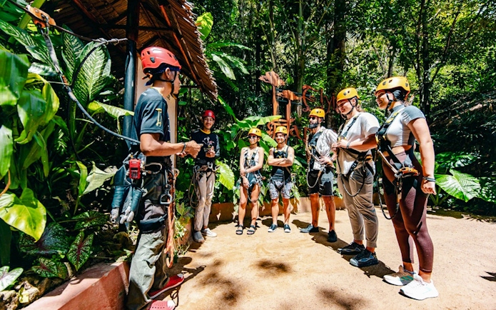 Group preparing for zipline adventure at Flying Hanuman, Phuket, wearing safety gear.
