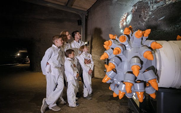 Visitors in protective suits exploring Hallein salt mines, Salzburg.