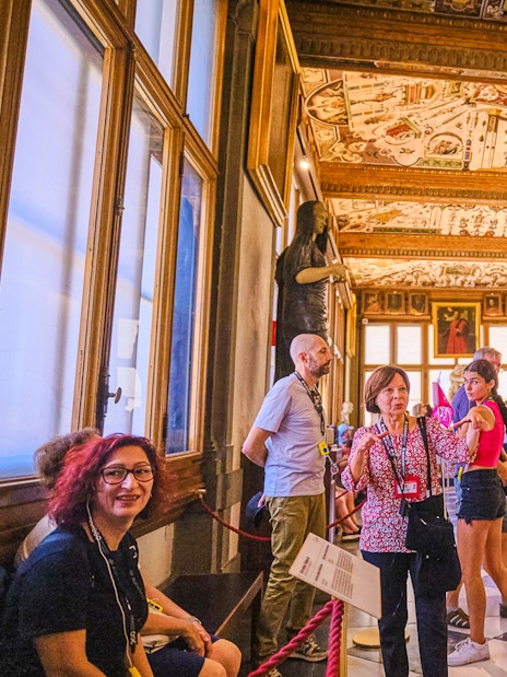 Tour group exploring the Vasari Corridor with art and sculptures, Florence, Italy.