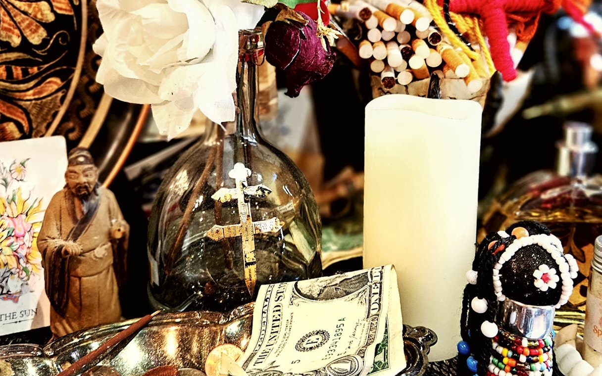 Voodoo artefacts with cross, candle, and figurine on New Orleans Haunted Ghost, Voodoo & Vampire Tour.